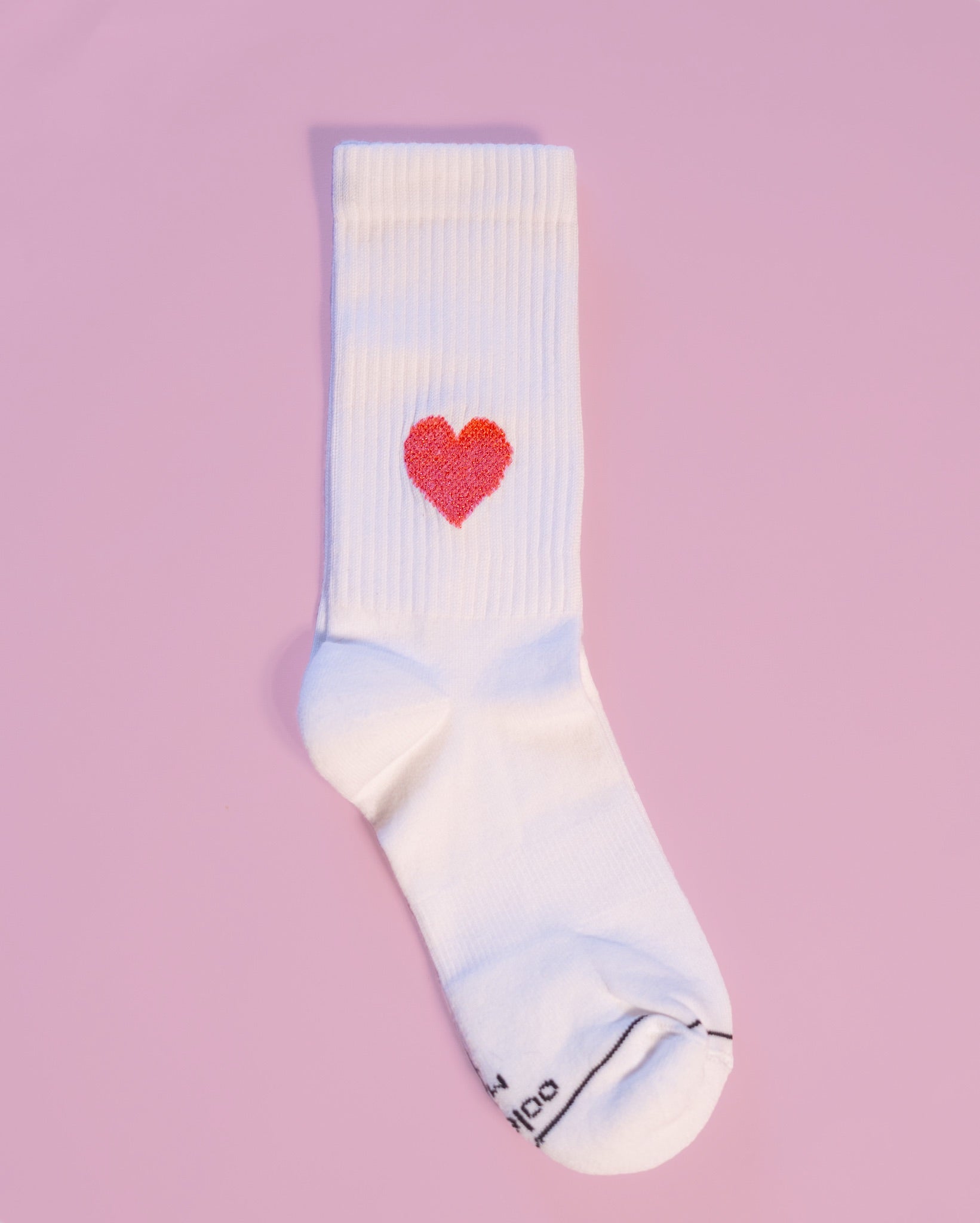 Weiße Socke mit rotem Herz auf rosa Hintergrund