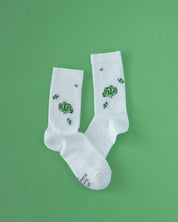 Weiße Socken mit Kaktus-Stickerei auf grünem Hintergrund.