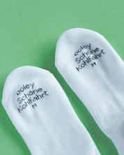 Weiße Socken mit Text auf grünem Hintergrund.