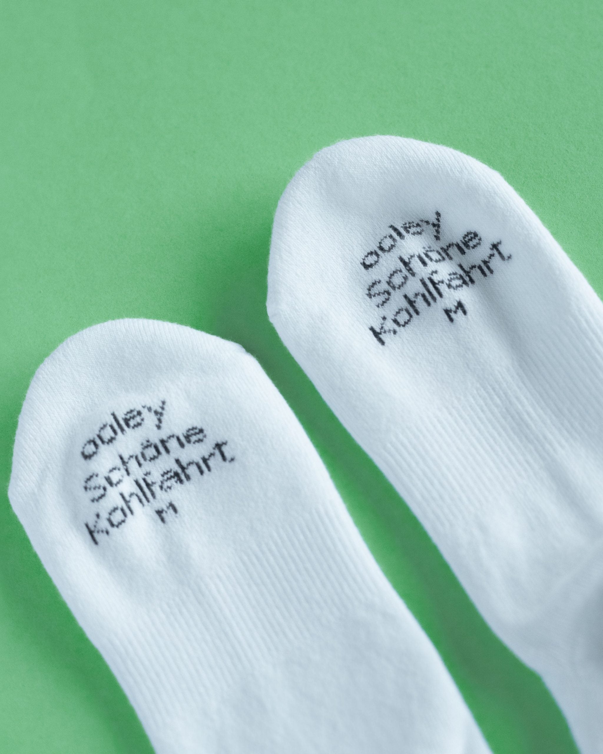 Weiße Socken mit Text auf grünem Hintergrund.