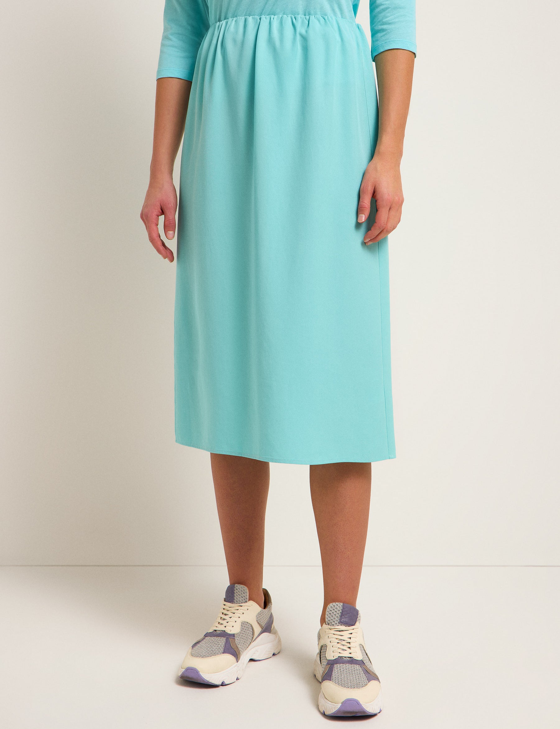 Frau in türkisem Kleid und Turnschuhen.