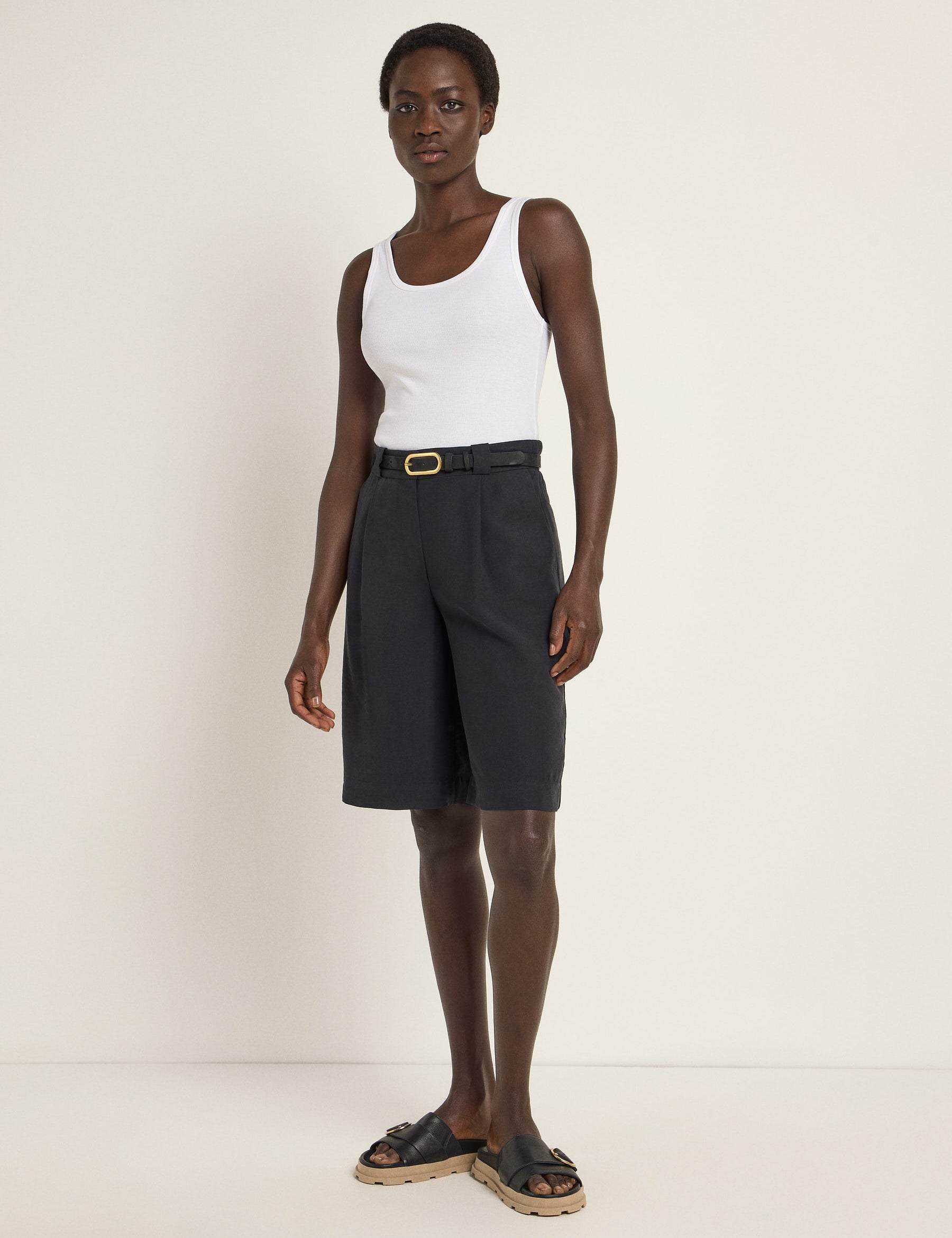 Frau in weißem Top und schwarzer Shorts steht