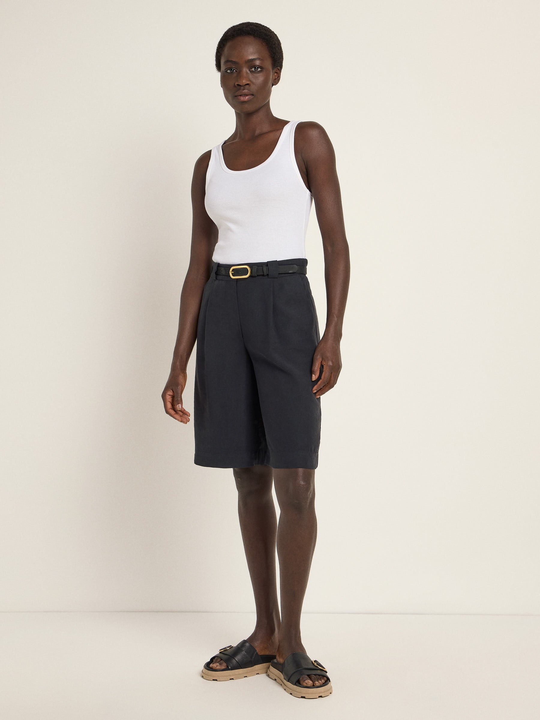 Frau in weißem Top und schwarzer Shorts steht