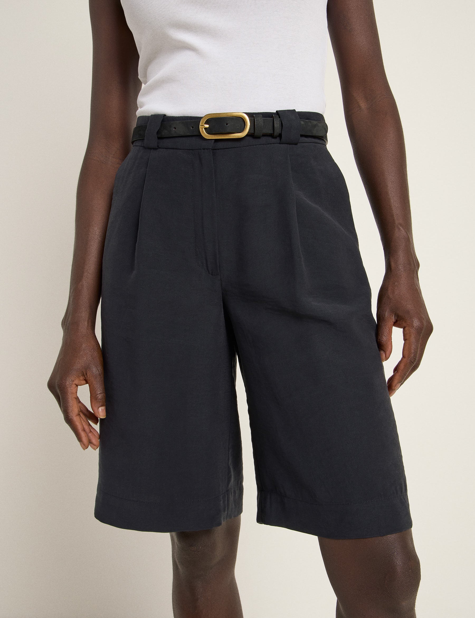 Person trägt dunkle Shorts mit Gürtel