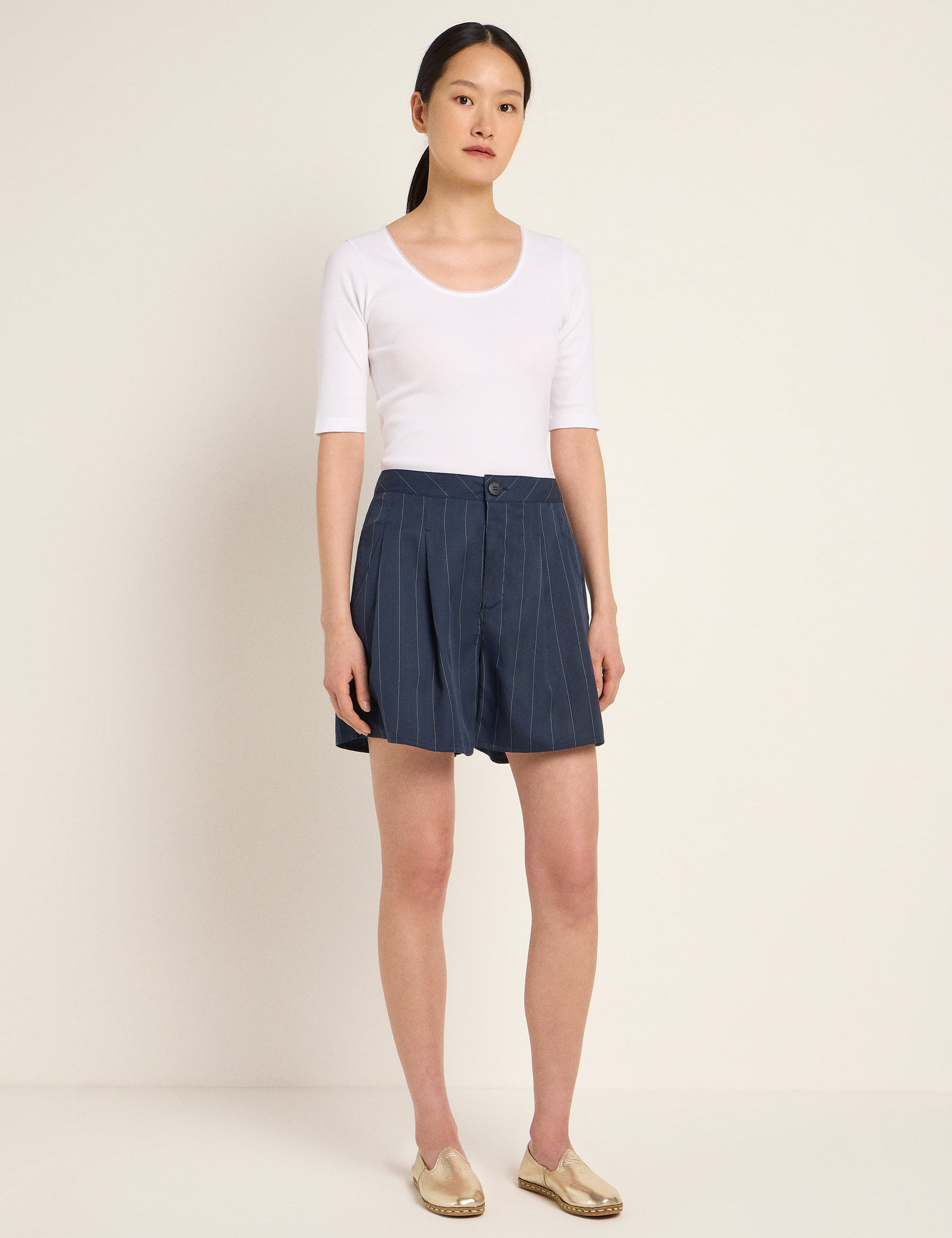 Frau in weißem Top und blauem Faltenrock