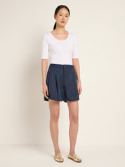 Frau in weißem Top und blauem Faltenrock
