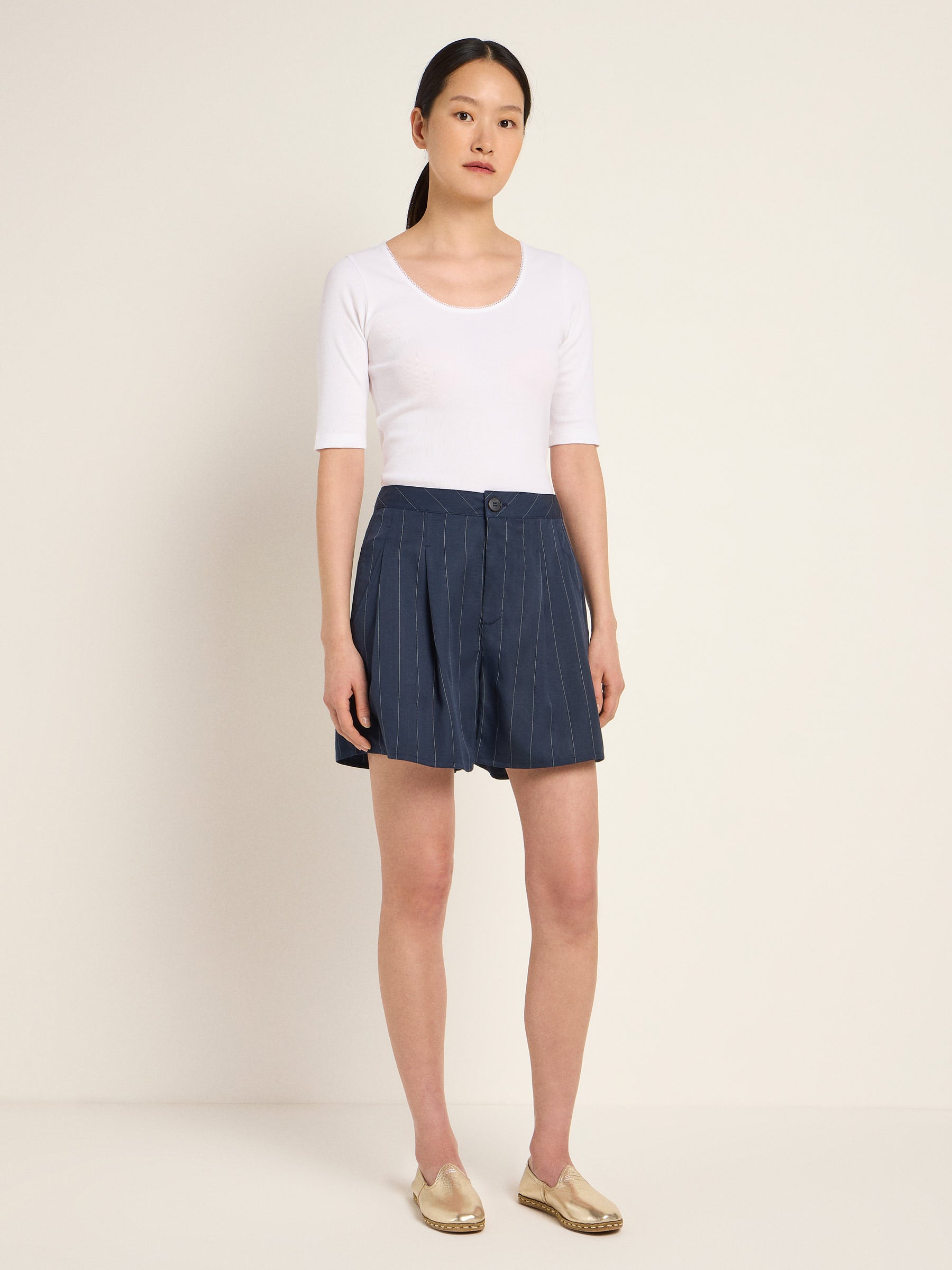 Frau in weißem Top und blauem Faltenrock