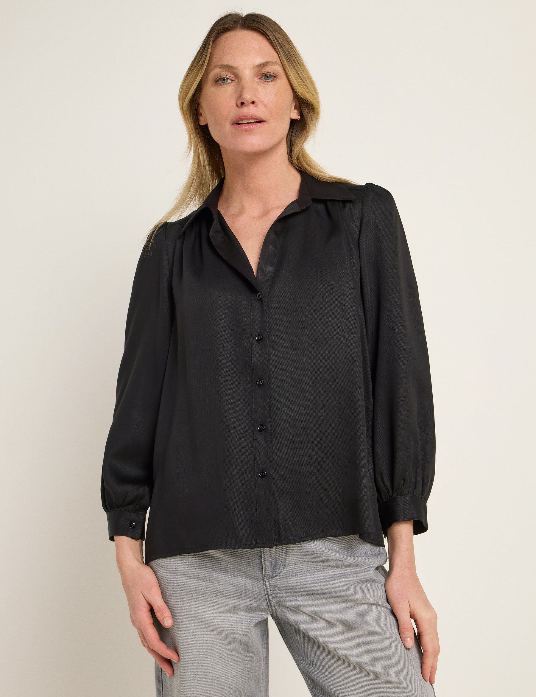 Frau in schwarzer Bluse und grauer Hose