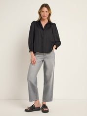 Frau in schwarzer Bluse und grauen Jeans