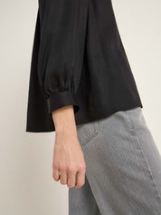 Detailaufnahme von Hand, schwarze Bluse, graue Hose