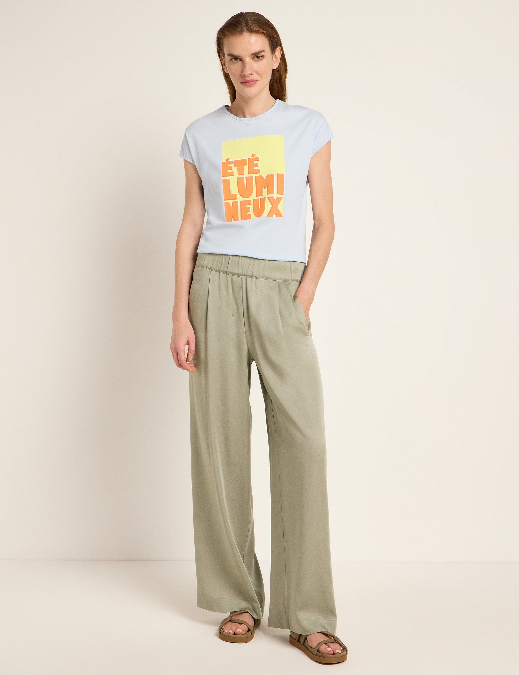 Frau in grüner Hose und bedrucktem T-Shirt