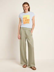 Frau in grüner Hose und bedrucktem T-Shirt