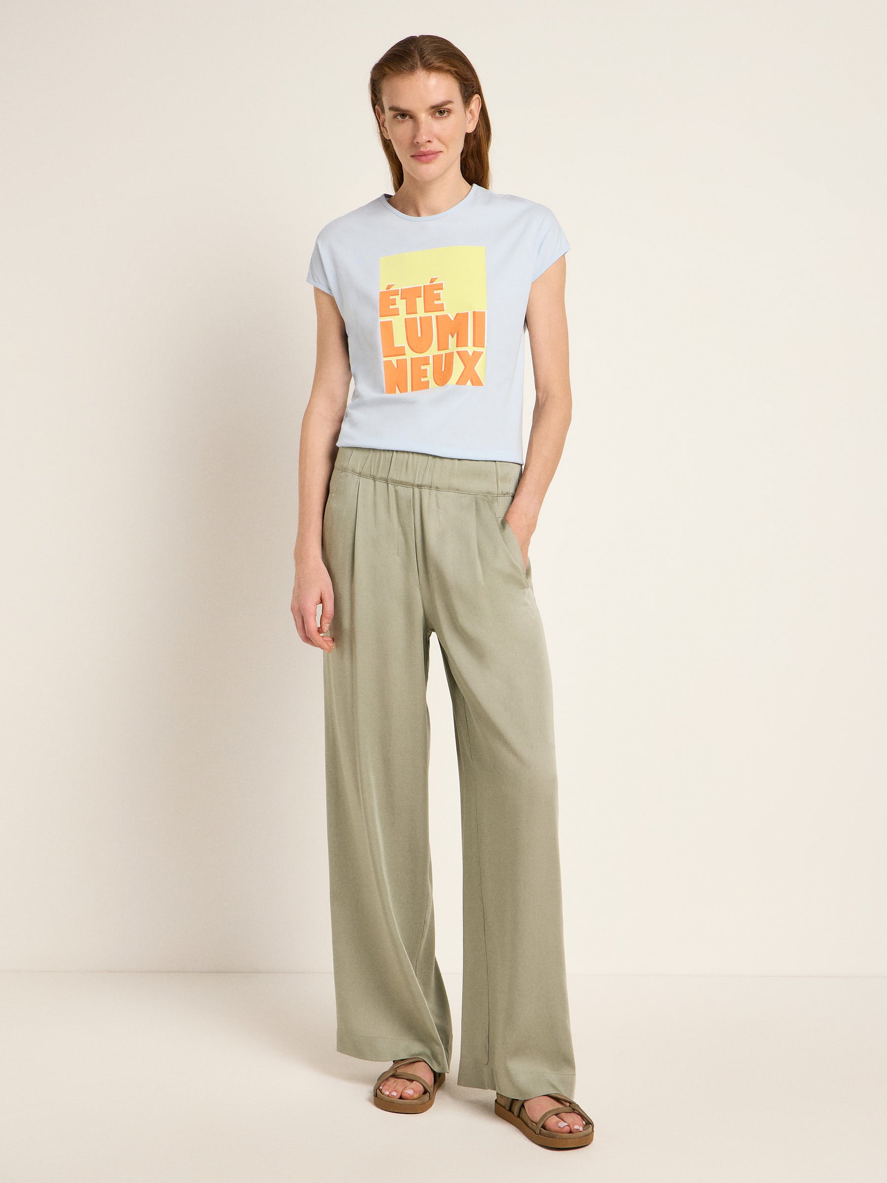 Frau in grüner Hose und bedrucktem T-Shirt