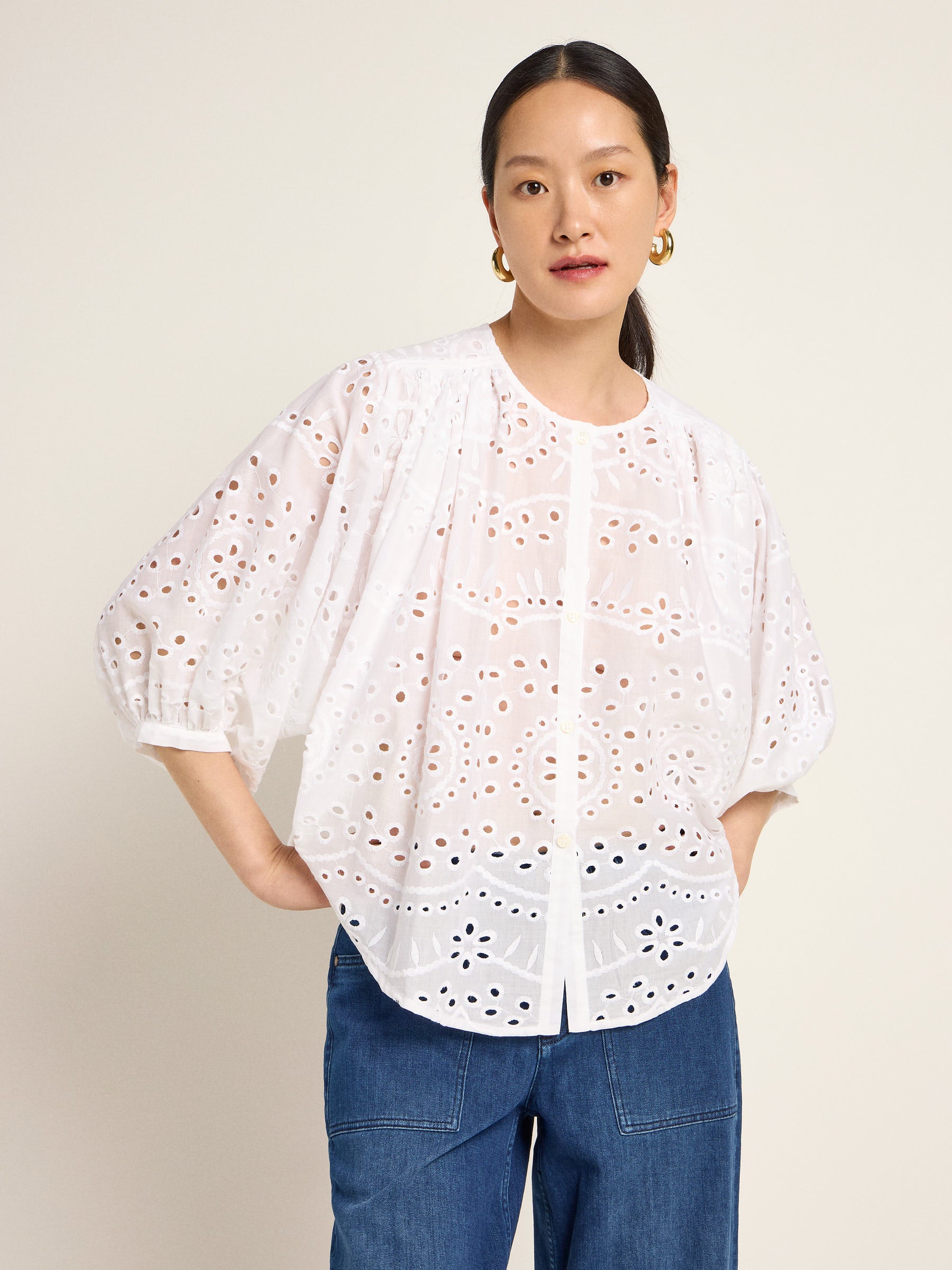 Frau in weißer Lochstickerei-Bluse und Jeans