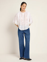 Frau in weißer Bluse und Jeans steht