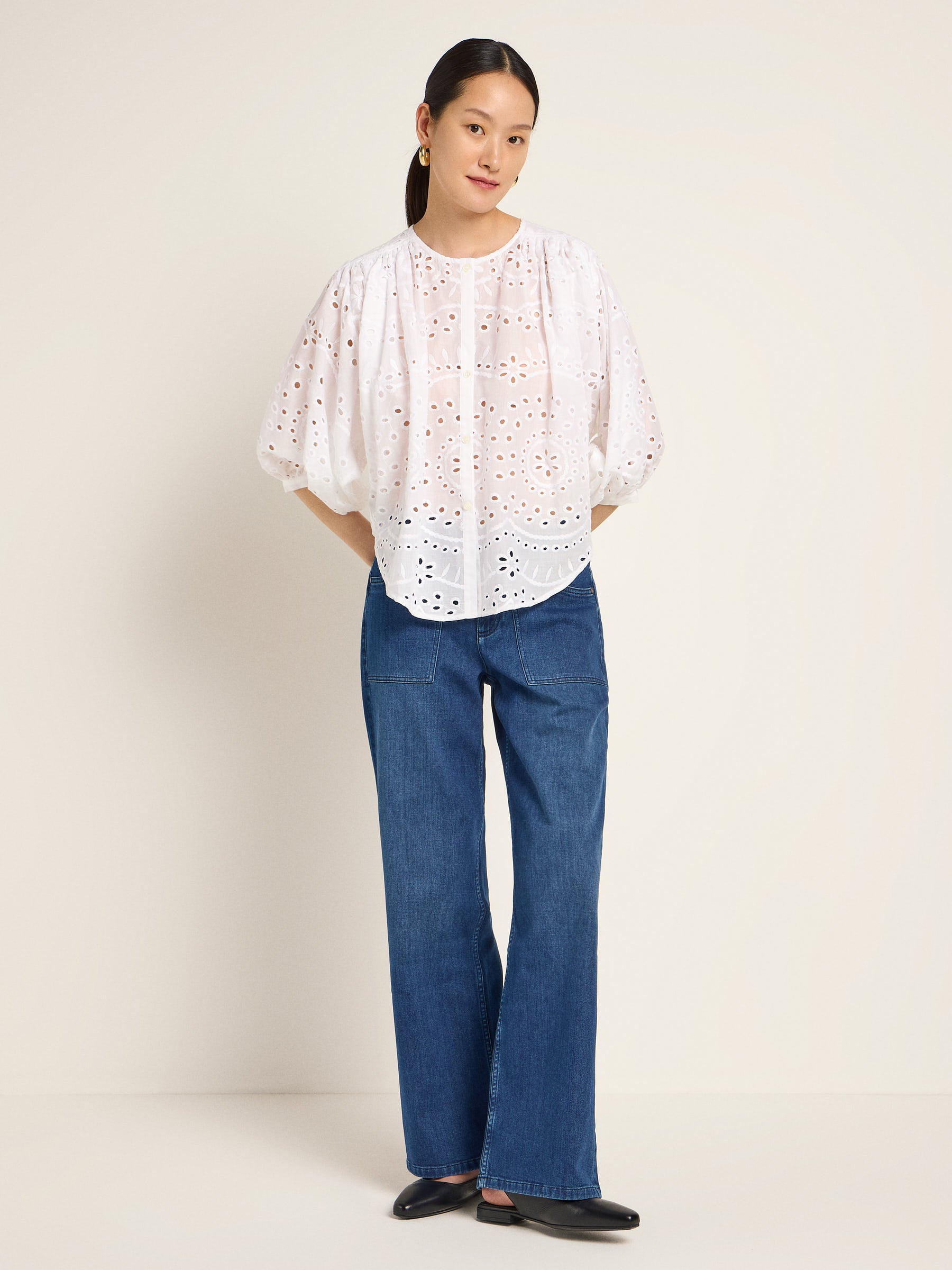 Frau in weißer Bluse und Jeans steht