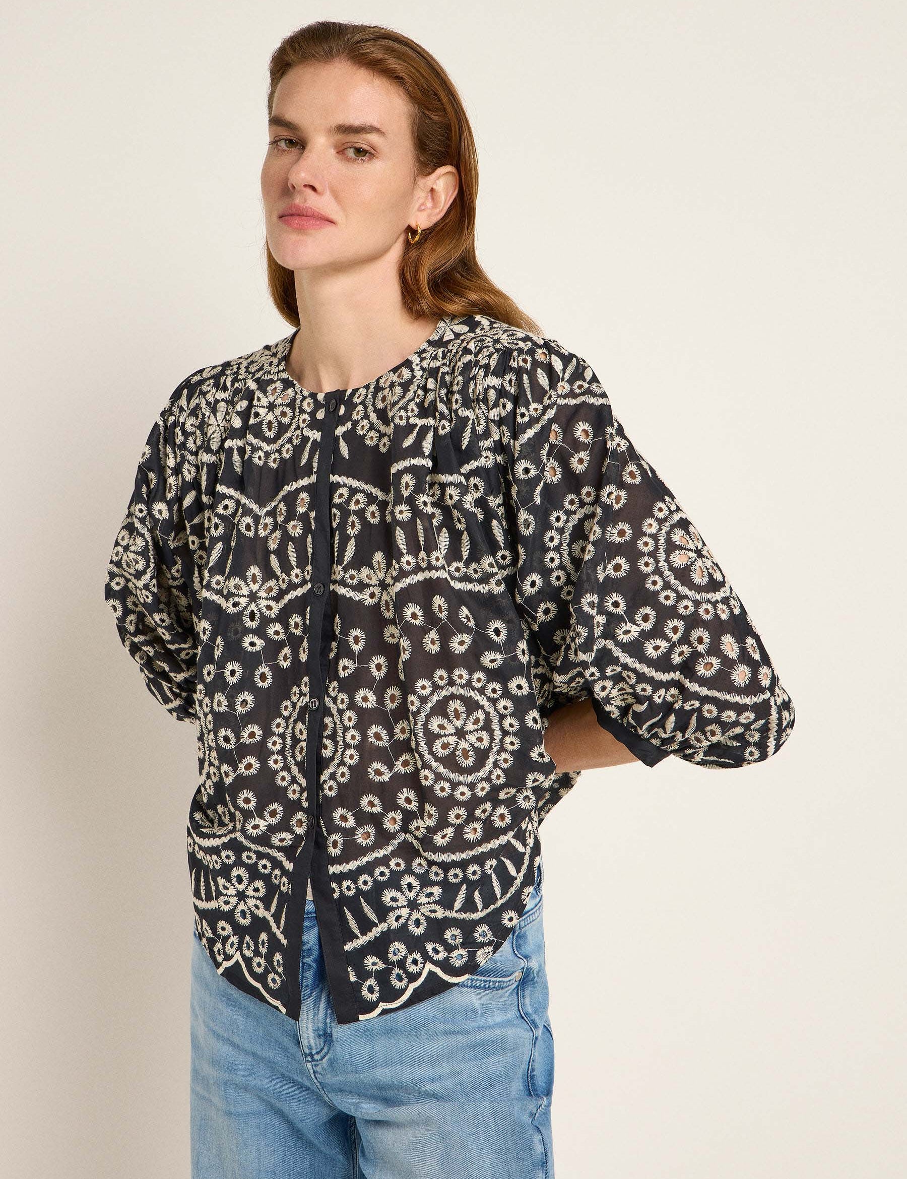 Frau in bestickter schwarzer Bluse und Jeans