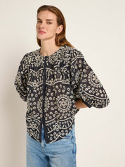 Frau in bestickter schwarzer Bluse und Jeans