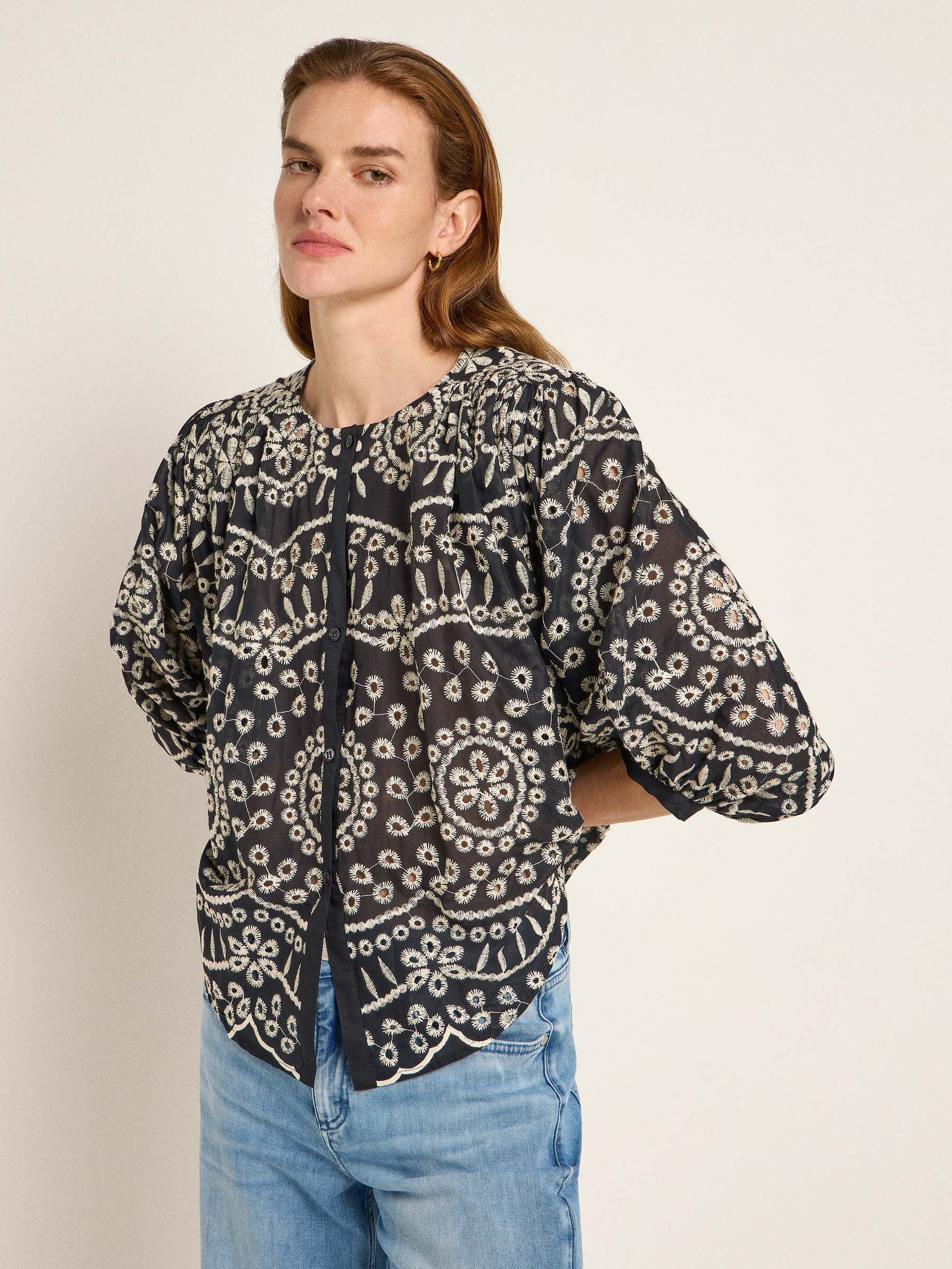 Frau in bestickter schwarzer Bluse und Jeans
