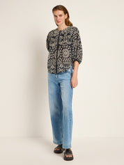Frau in gemusterter Bluse und Jeans