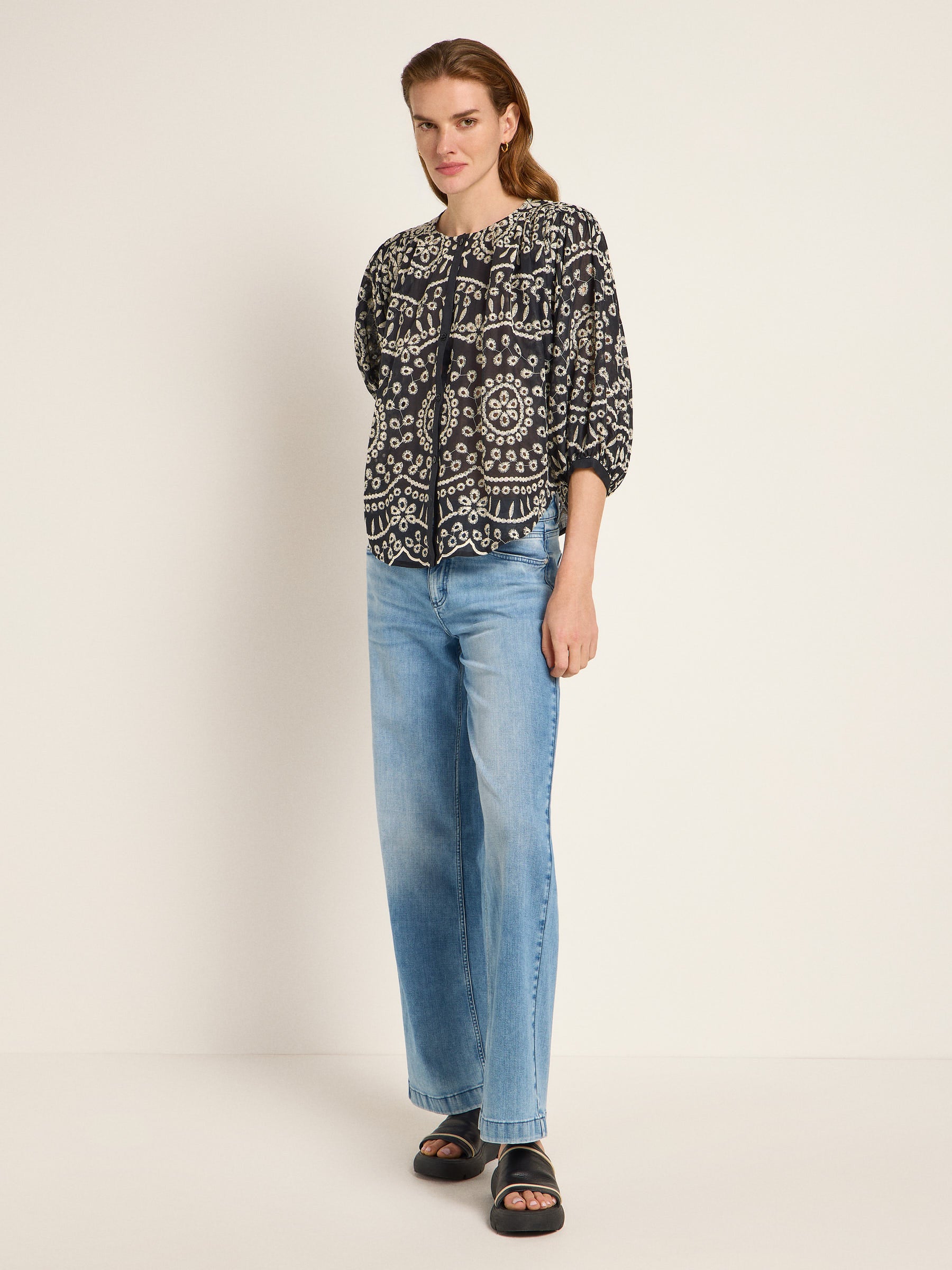 Frau in gemusterter Bluse und Jeans