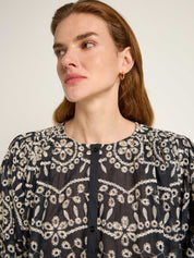 Frau mit bestickter Bluse und goldener Ohrring