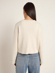 Frau trägt beigefarbenen Pullover und blaue Jeans