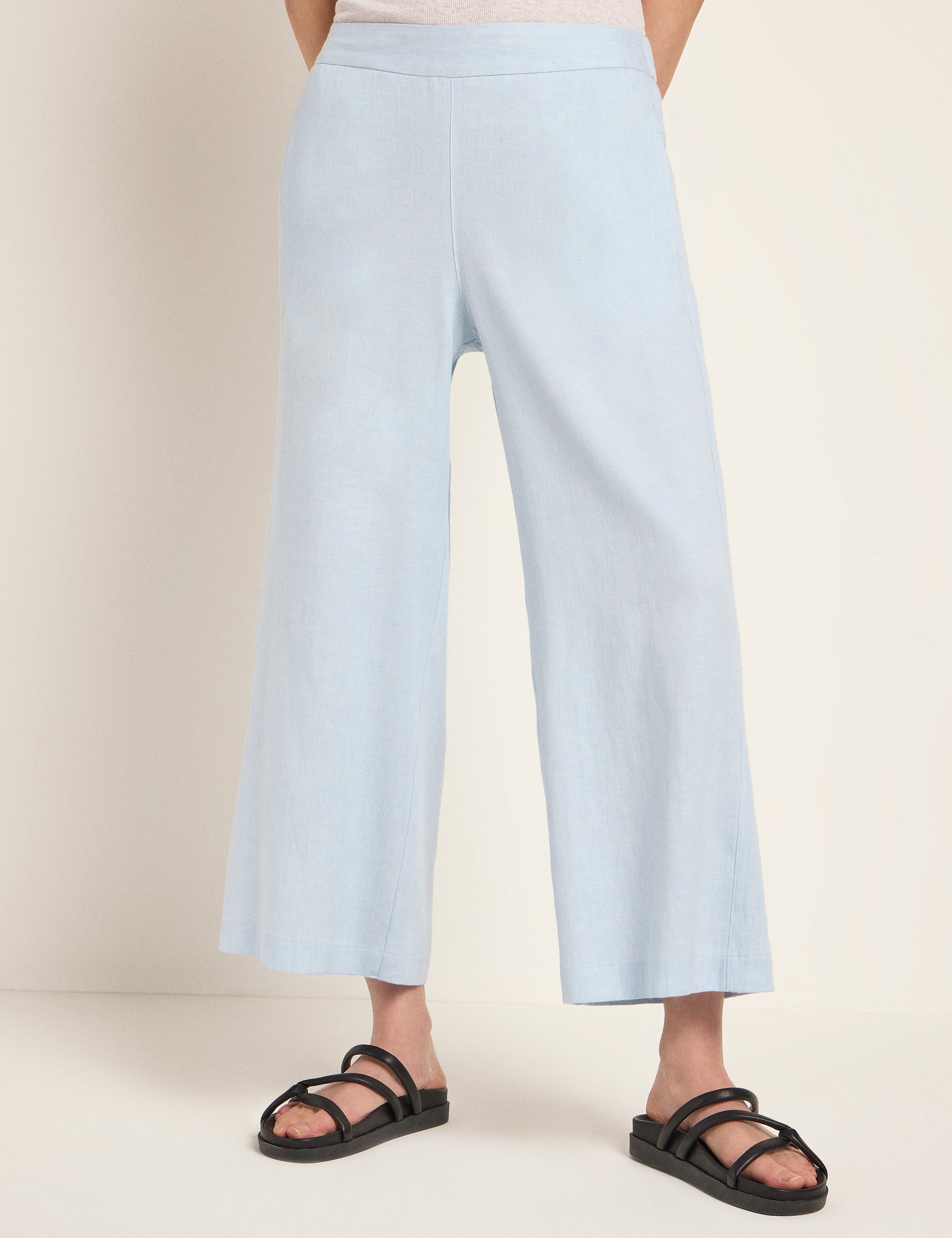 Frau in hellblauen Culottes und schwarzen Sandalen