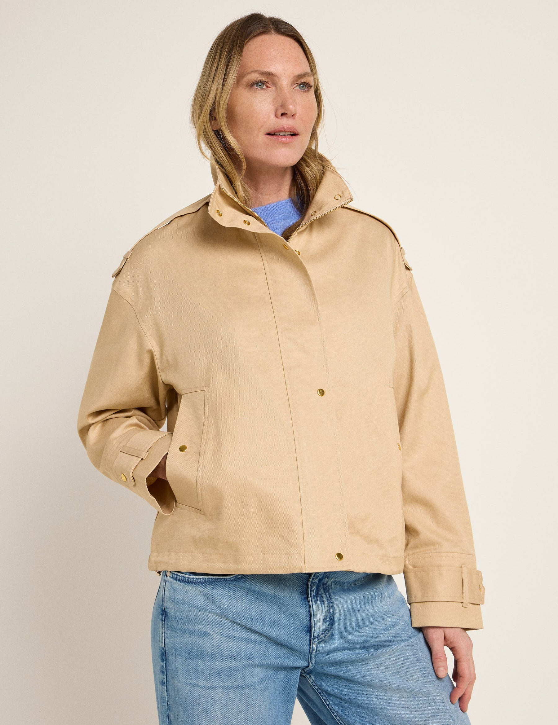 Frau in beiger Jacke und blauer Jeans