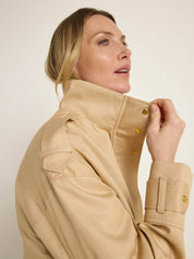 Frau in beiger Jacke blickt seitlich