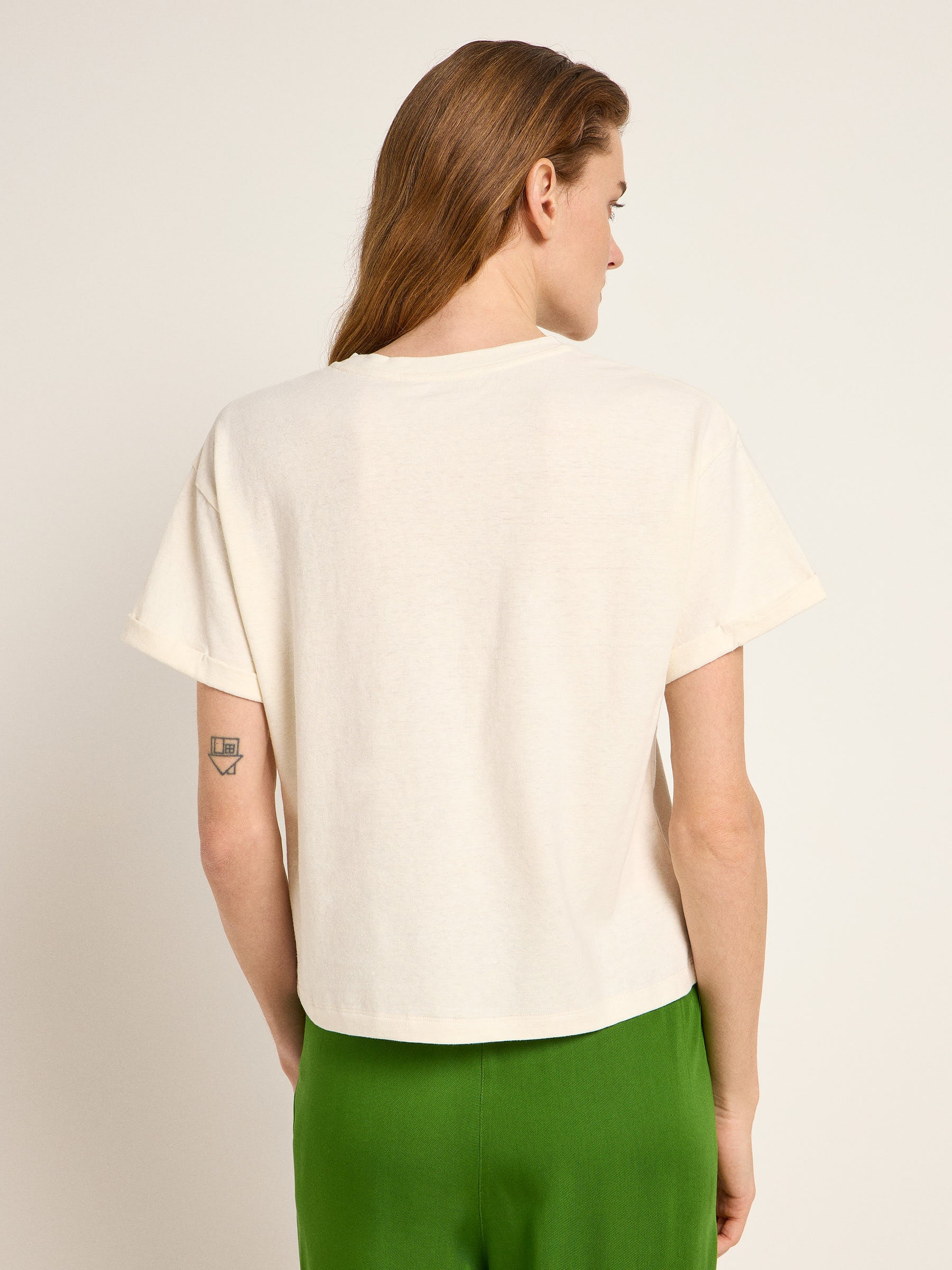 Frau von hinten in weißem T-Shirt und grüner Hose