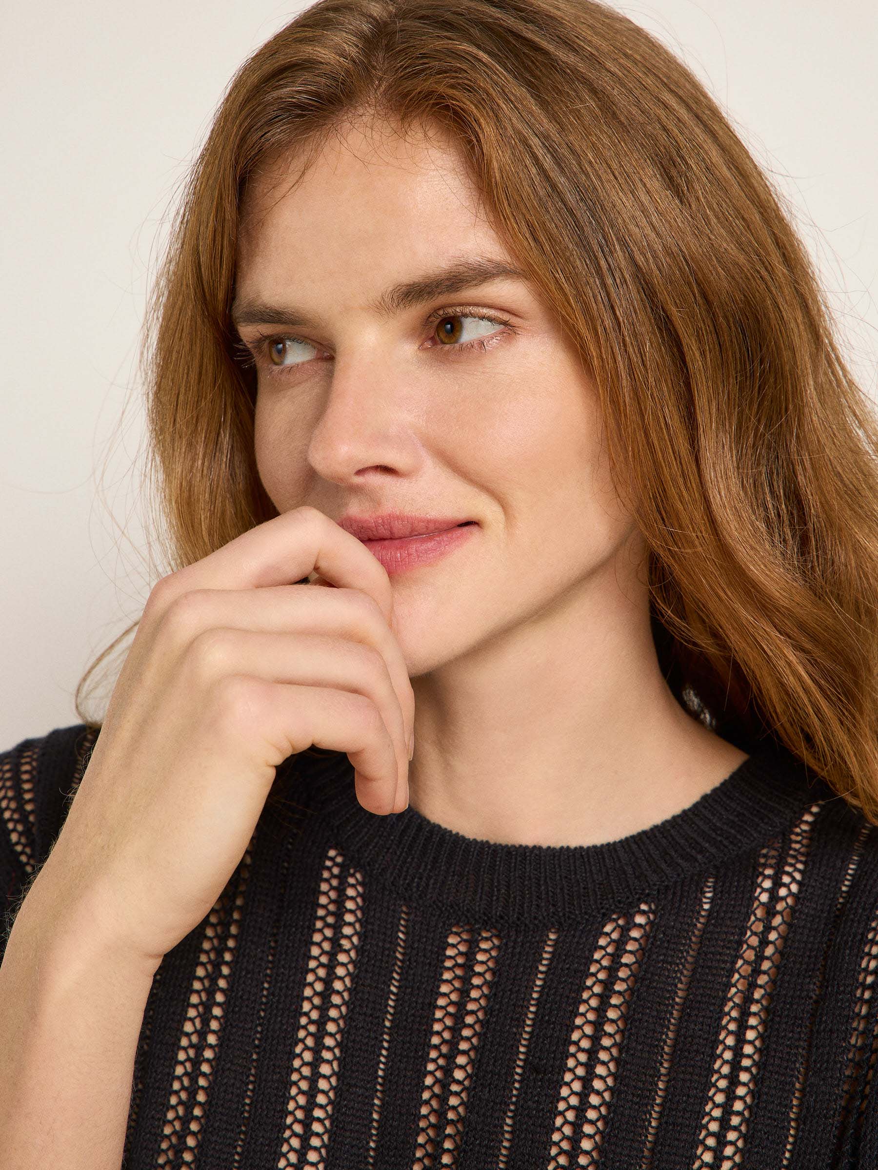 Nachdenkliche Frau in schwarzem Strickpullover