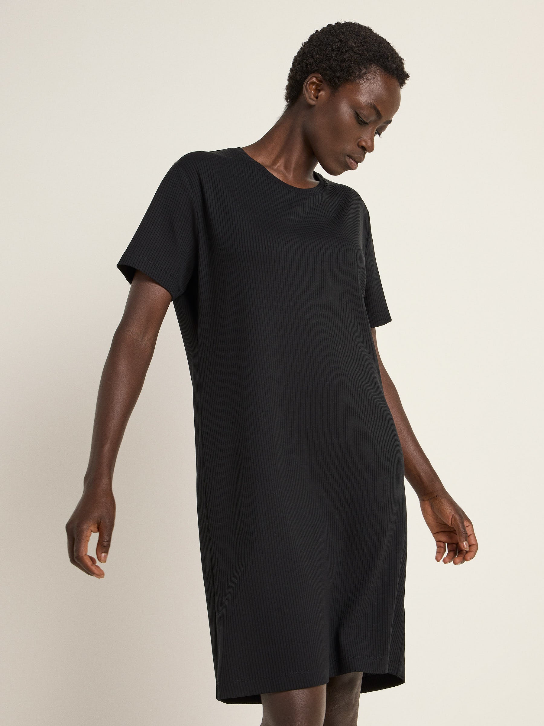 Frau in schwarzem Kleid steht elegant