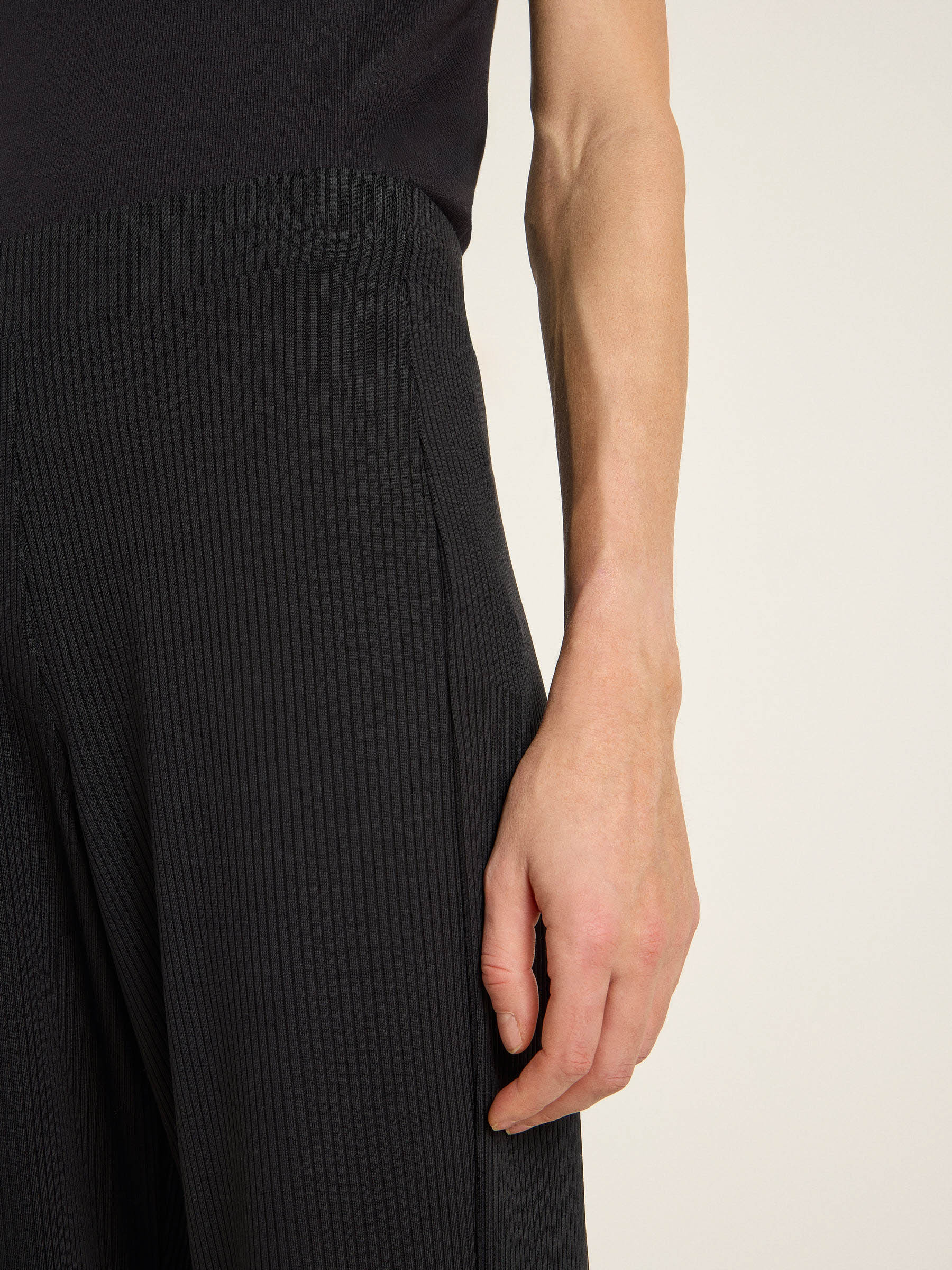 Detailaufnahme von Arm in schwarzer Rippstrickkleidung