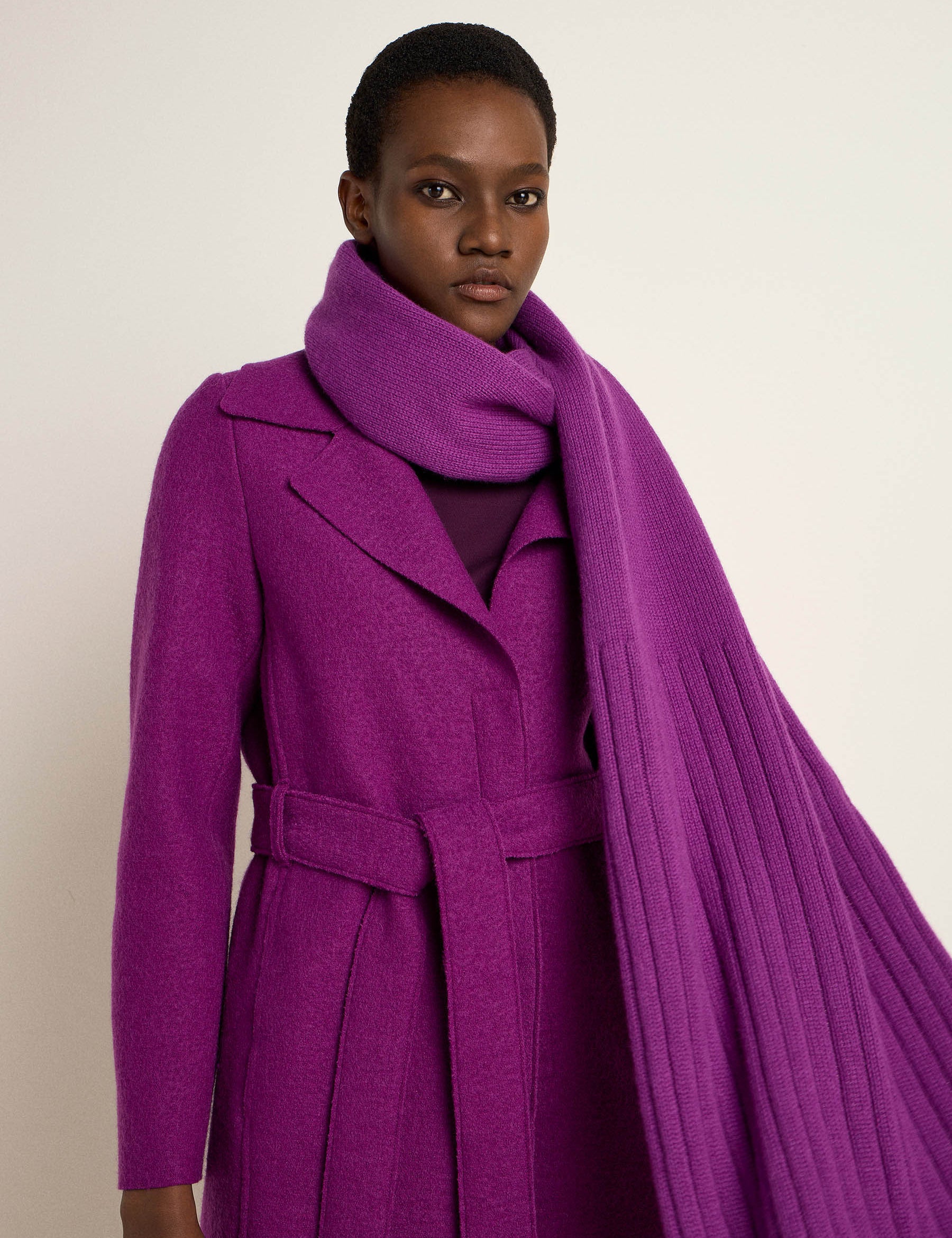 Frau in elegantem lila Mantel und Schal