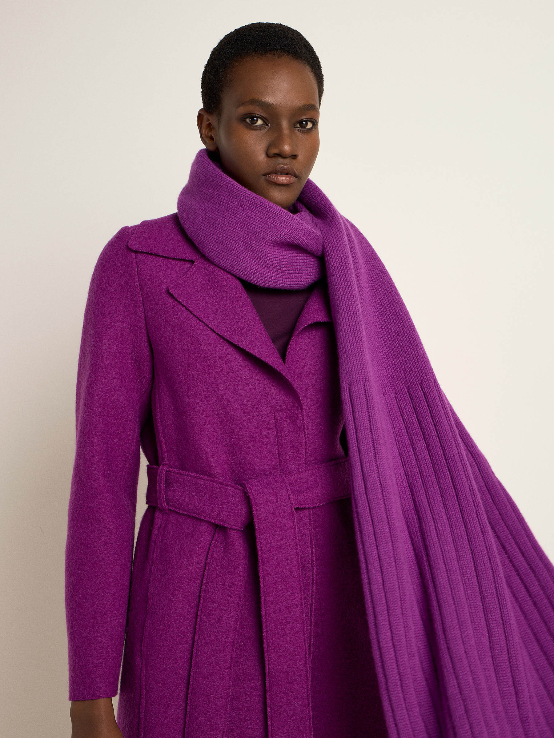 Frau in elegantem lila Mantel und Schal