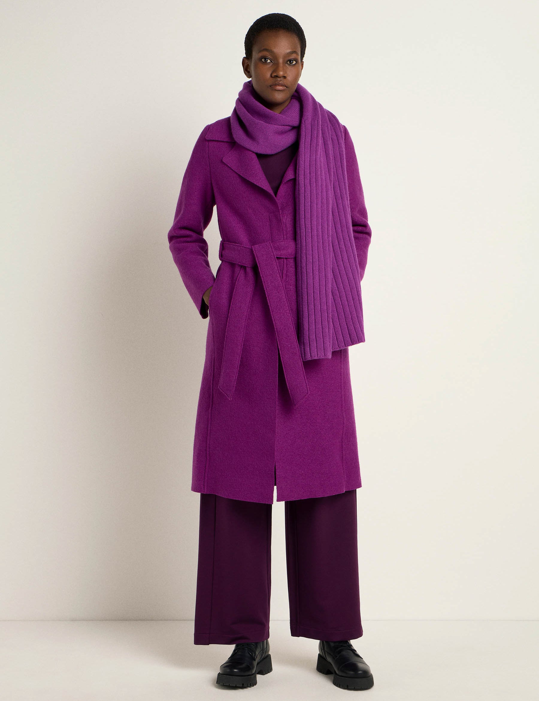 Frau in lila Mantel und Schal posiert