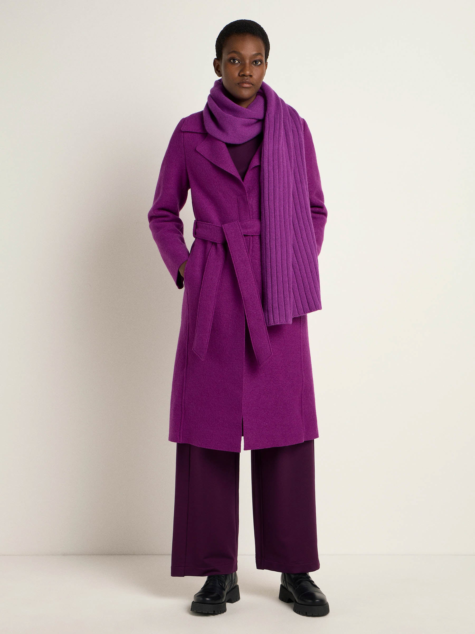 Frau in lila Mantel und Schal posiert
