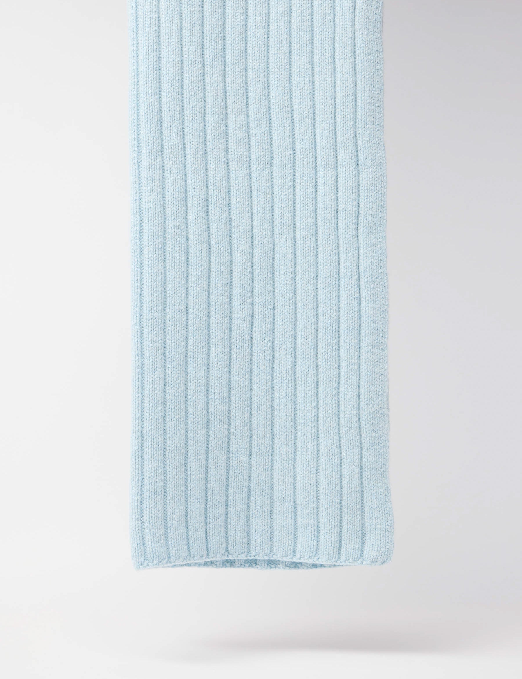 Blaue gestrickte Wolldecke an weißer Wand