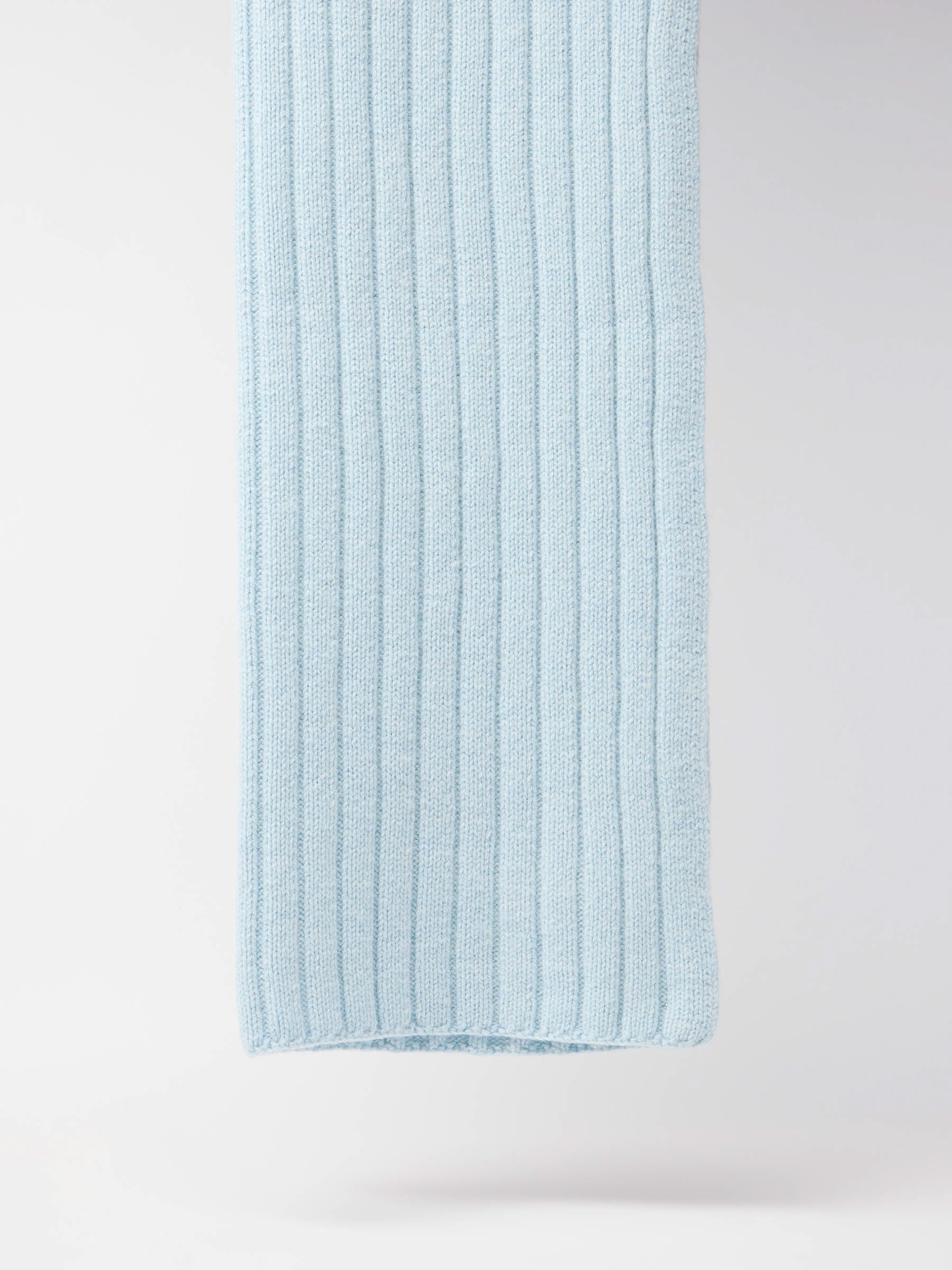 Blaue gestrickte Wolldecke an weißer Wand