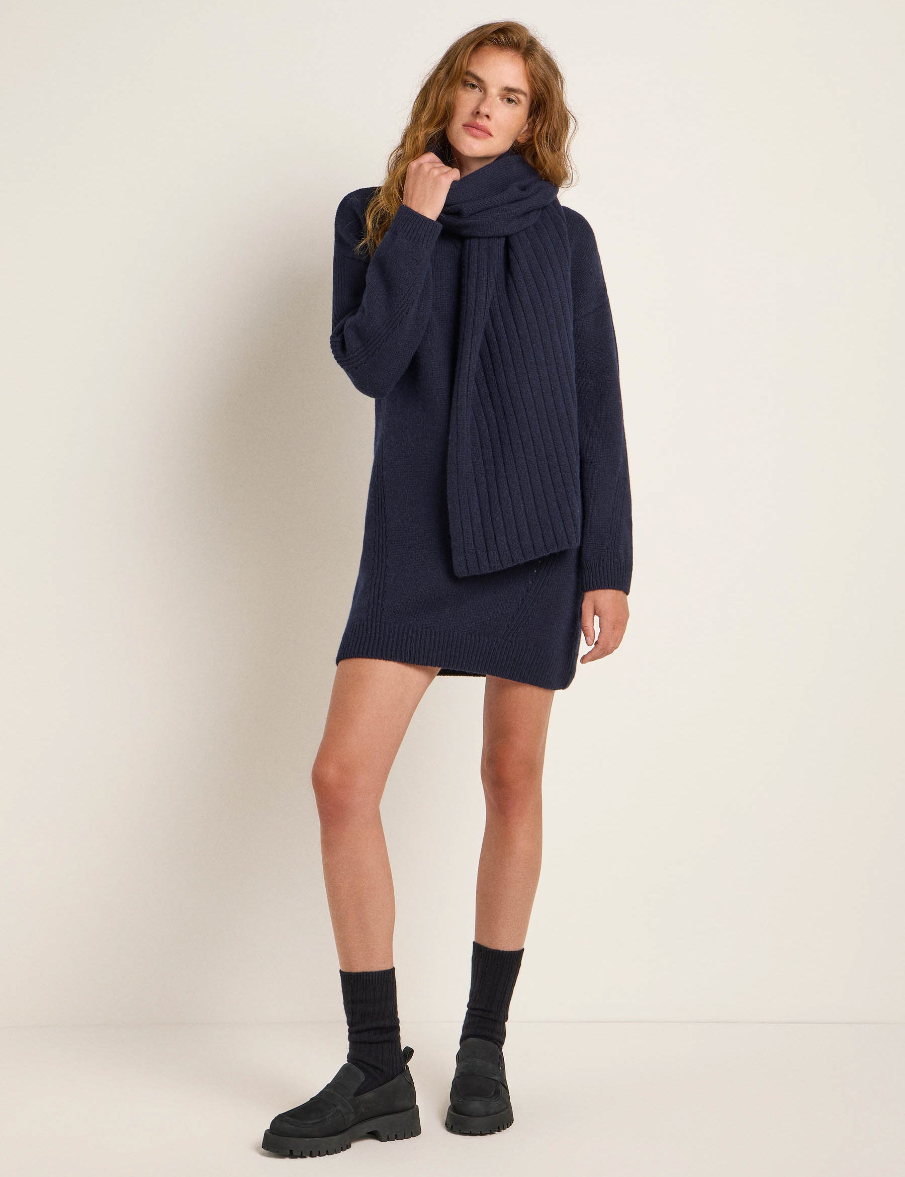 Frau in dunklem Strickkleid und Schal posiert