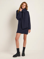 Frau in dunklem Strickkleid und Schal posiert