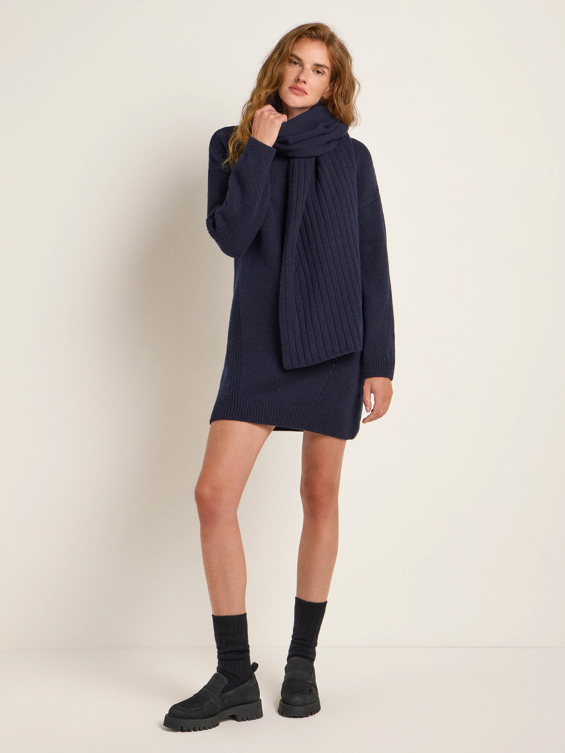 Frau in dunklem Strickkleid und Schal posiert