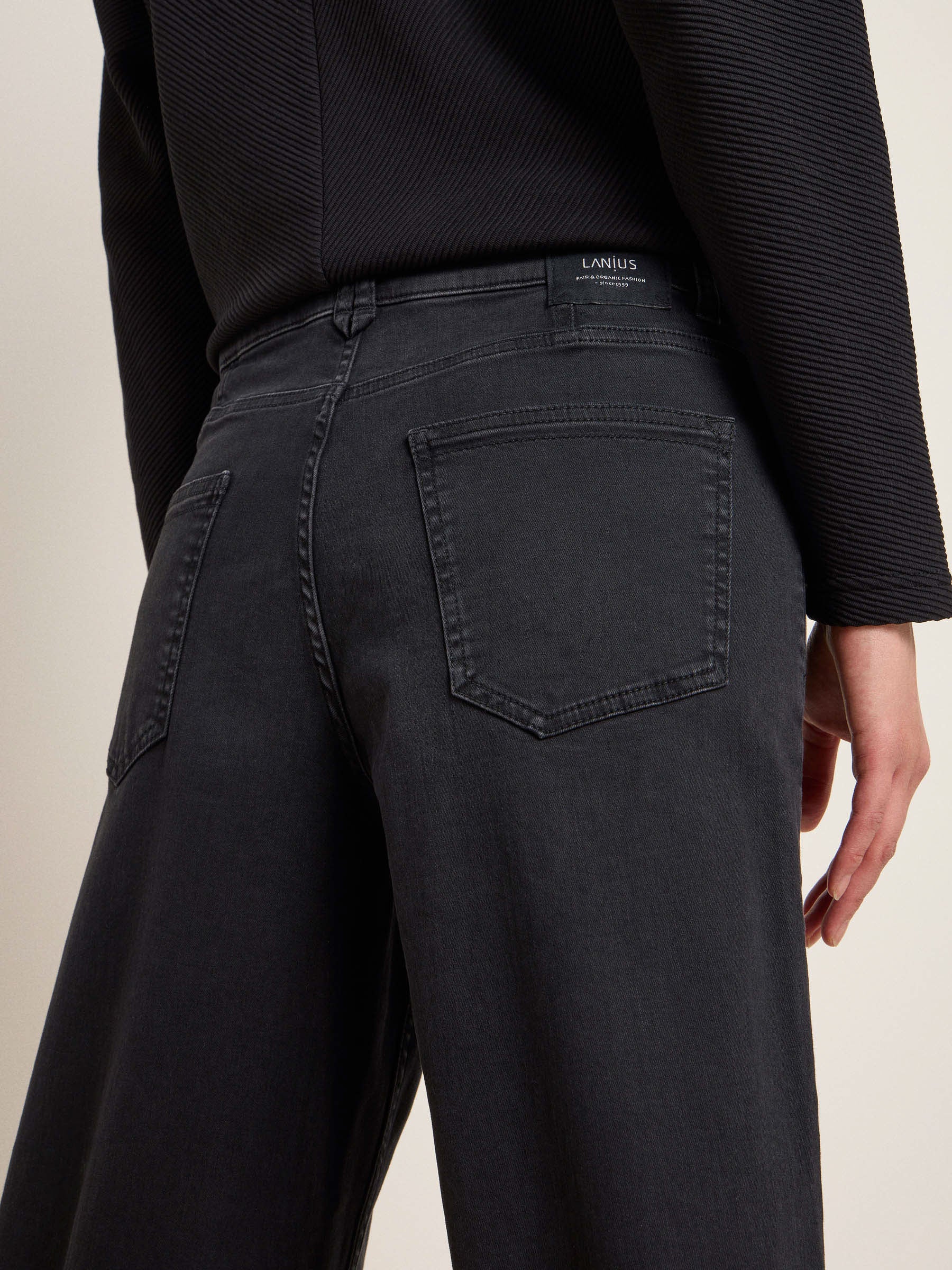 Person trägt schwarze Jeans und schwarzes Top