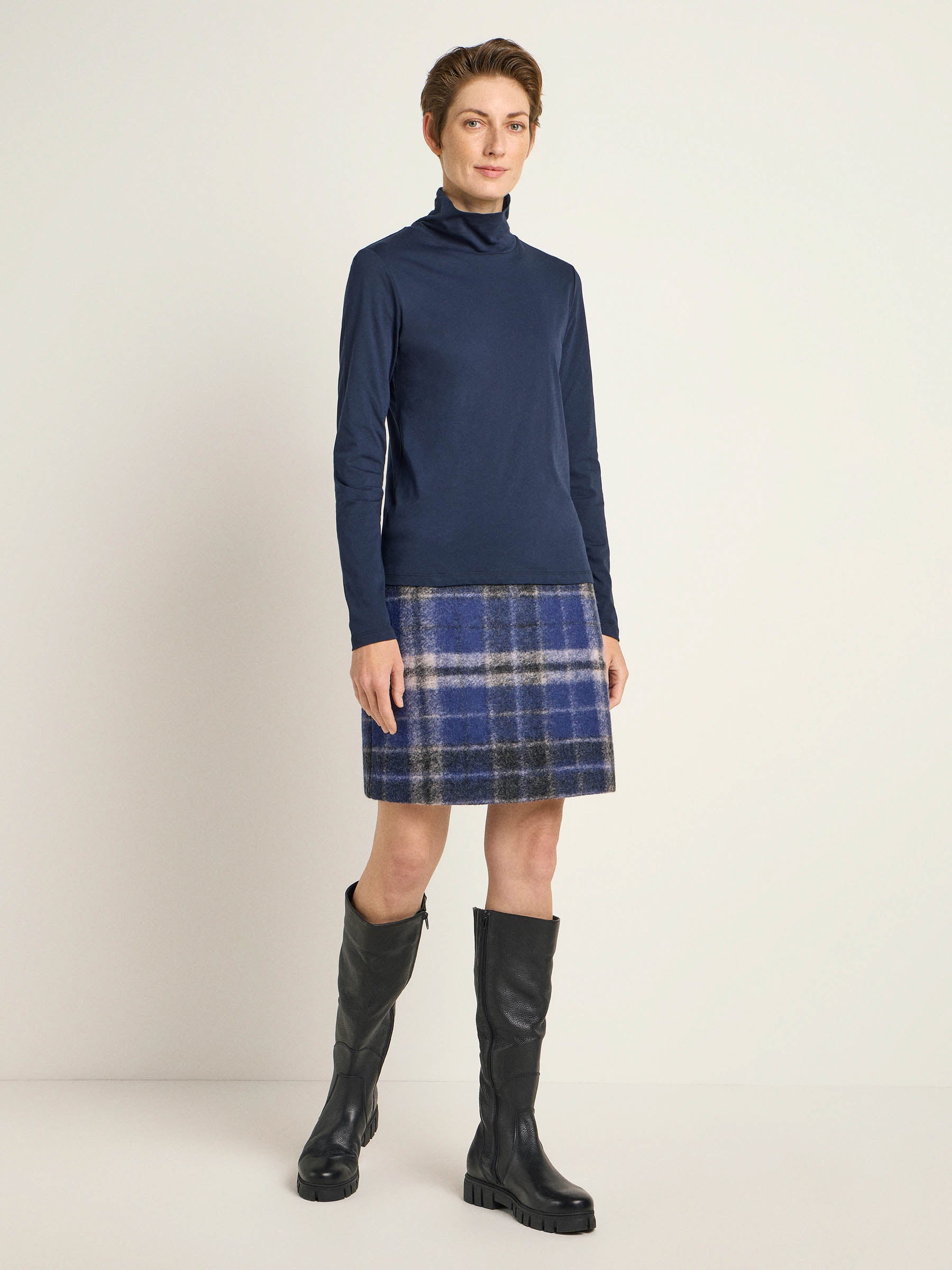 Frau in Rollkragenpullover und kariertem Rock