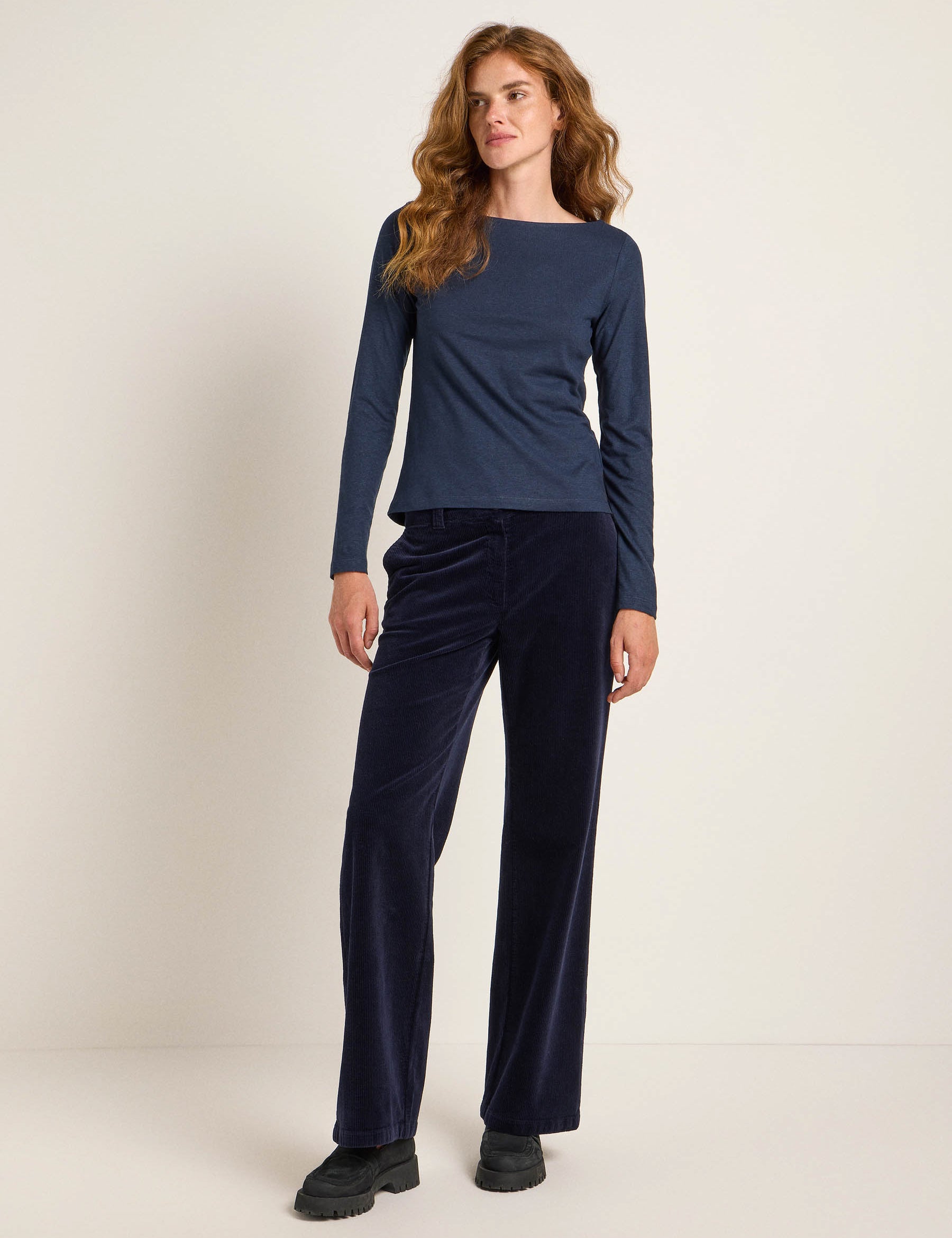 Frau in blauem Oberteil und dunkler Hose steht