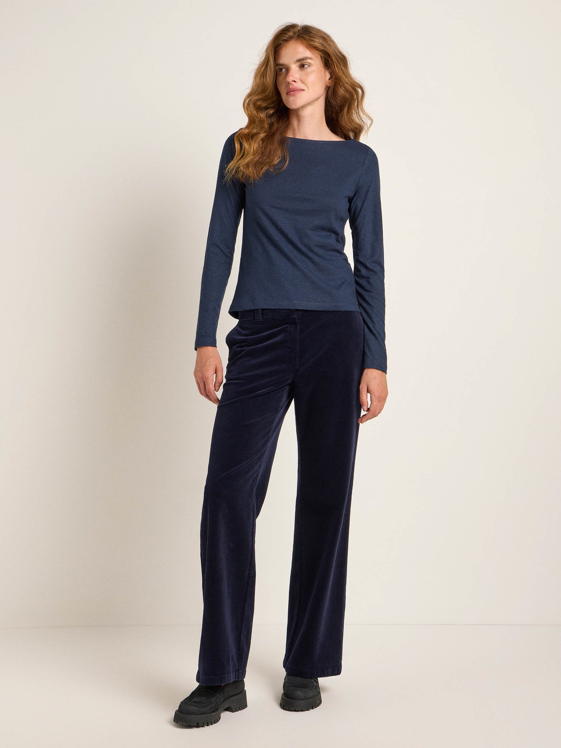 Frau in blauem Oberteil und dunkler Hose steht