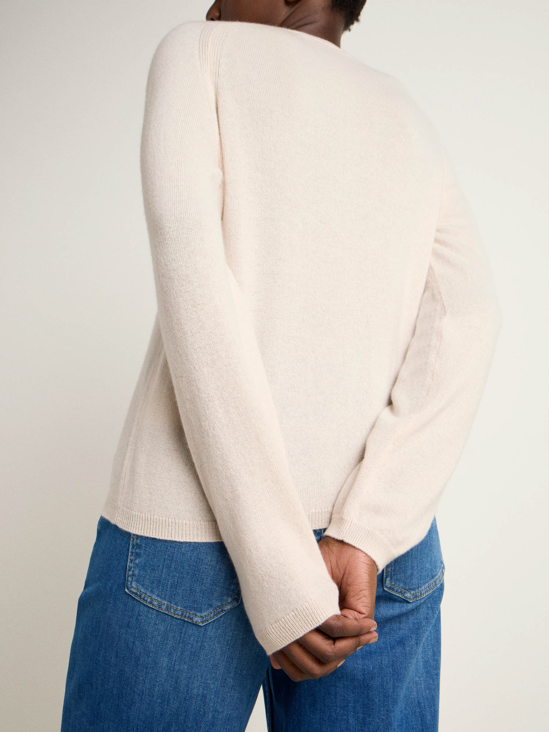Person trägt weißen Pullover und Jeans