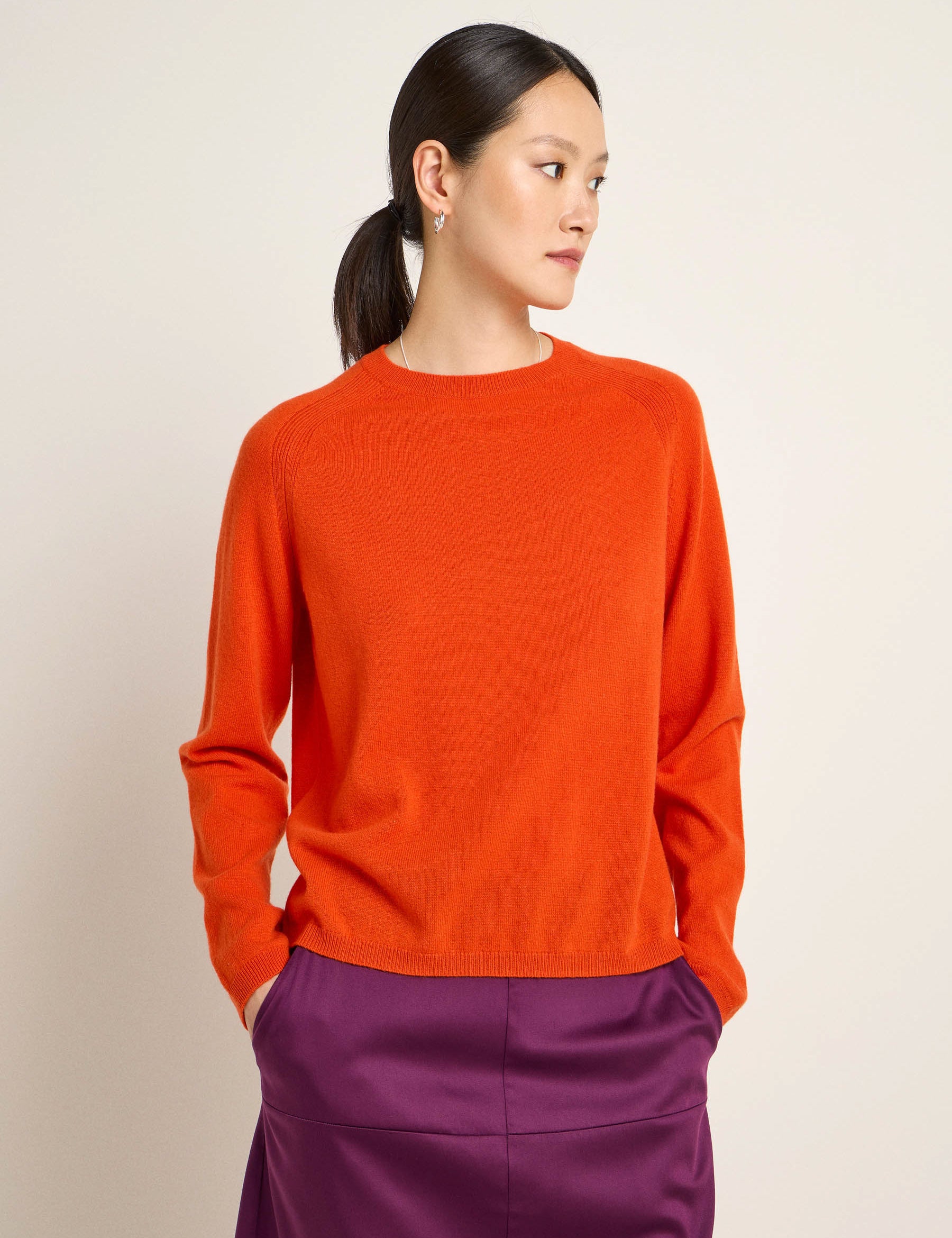 Frau in orangenem Pullover und lila Rock