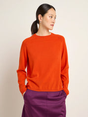 Frau in orangenem Pullover und lila Rock